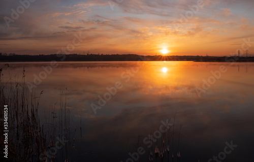 Gorgeous sunrise over the lake with reflection of the sun on the lake and spring