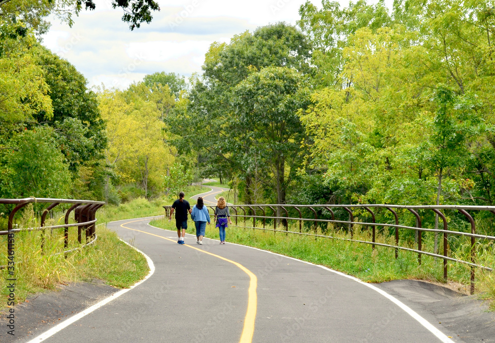 Three walkers enjoying the beautiful Greenway Trail that runs from East Setauket to Port Jefferson Station on Long Island, NY.  Copy space.