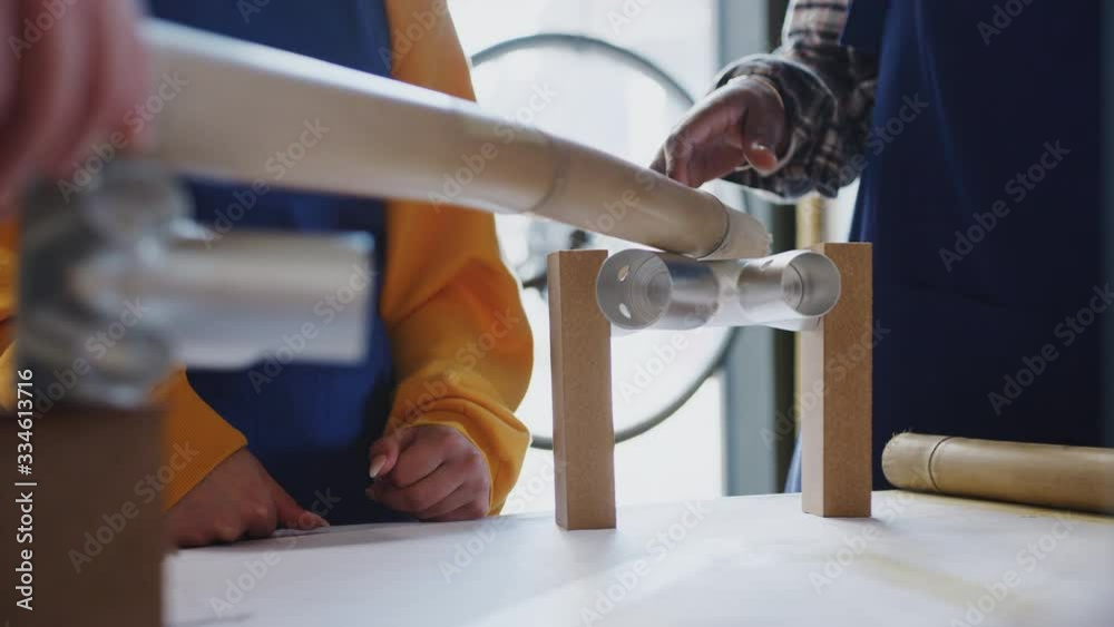 Close up of multi-cultural team of trainees in workshop learning how to assemble hand built bamboo bicycle frame together - shot in slow motion Close up of multi-cultural team of trainees in workshop learning how to assemble hand built bamboo bicycle frame together - shot in slow motion