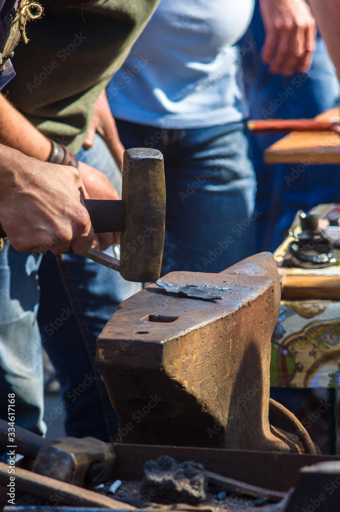 blacksmith performs the forging of hot glowing metal on the anvil blacksmith performs the forging of hot glowing metal on the anvil
