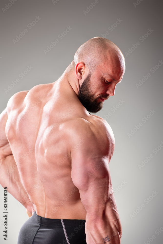 Close up of sexy muscular bodybuider posing on the gray background. Triceps contraction Close up of sexy muscular bodybuider posing on the gray background. Triceps contraction
