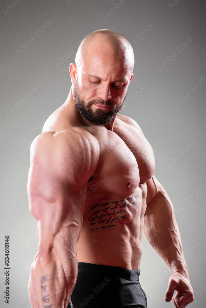Close up of sexy muscular bodybuider posing on the gray background. Triceps contraction