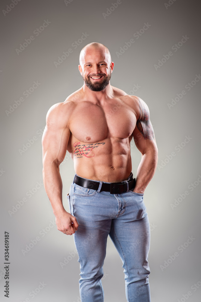Sexy muscular bodybuider posing on the gray background Sexy muscular bodybuider posing on the gray background