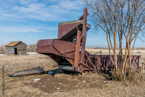 Vintage pull-type combine and granary abandoned in a field in Saskatchewan  Canada