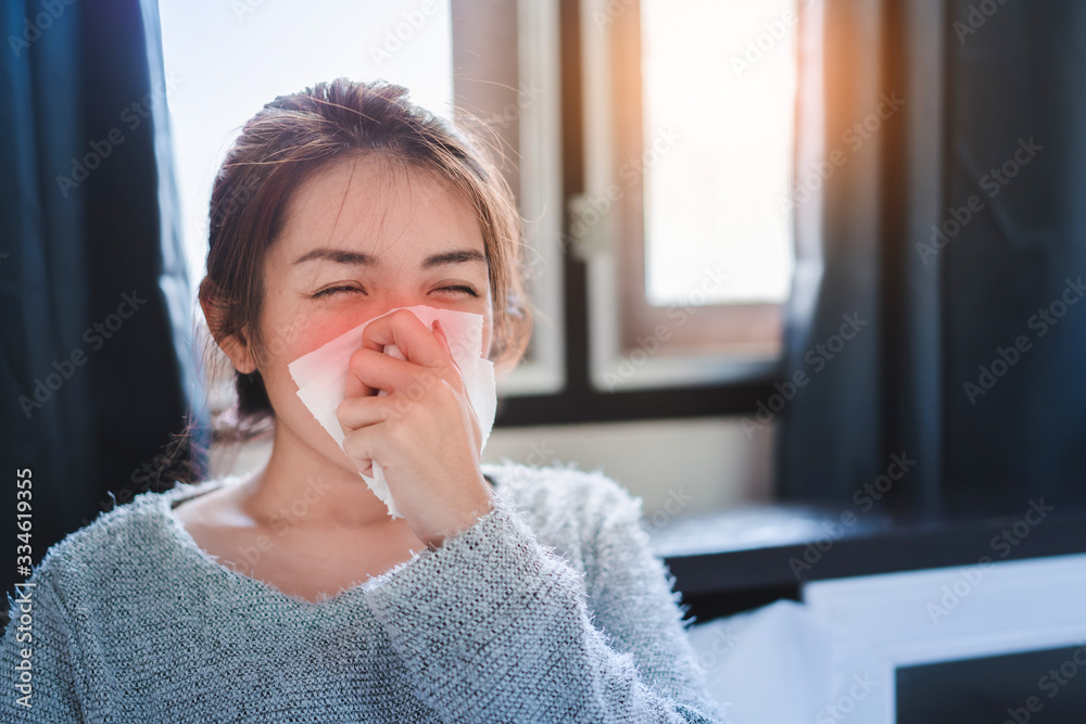 Sick asian woman have hight fever flu and sneezing into tissue on bed in bedroom, ,Global healthcare and prevent the spread infection corona virus concept, Selective focus. Sick asian woman have hight fever flu and sneezing into tissue on bed in bedroom, ,Global healthcare and prevent the spread infection corona virus concept, Selective focus.