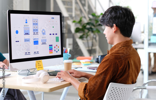 Website designer, Creative planning phone app development template layout framework wireframe design, User experience concept, Young asian man UX designer working on smartphone application at office photo