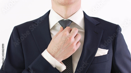 Businessman adjusting his necktie and jacket, close up.