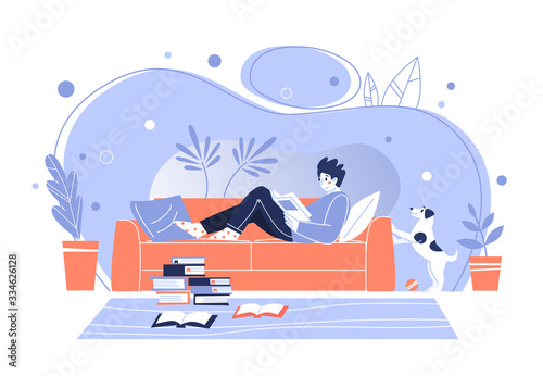  man at home, lying on the sofa, reading books. Home library. The concept of reading paper literature. Young adult man having a rest with good book. Boy enjoying himself at home.