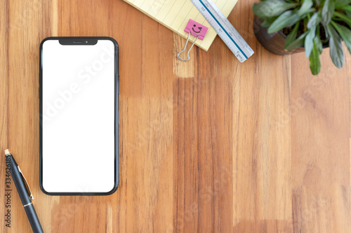 Smartphone with blank white copy space for text, Mockup design desktop computer in office on wood table desktop, Work place concept, Ornamental plant in pot.