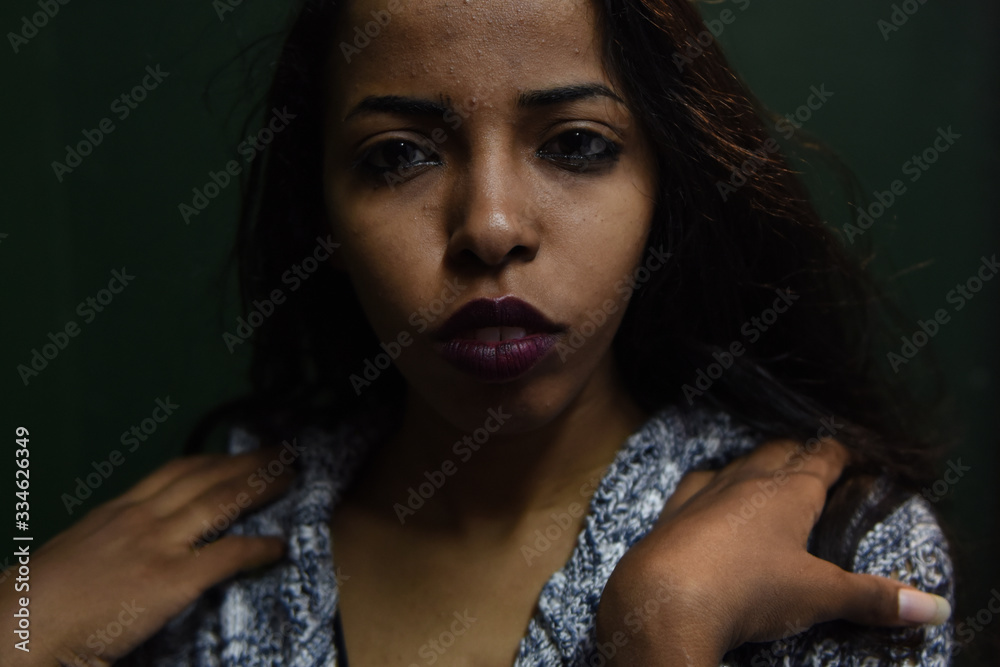 young African woman posing at studio, face with hand portrait over dark background young African woman posing at studio, face with hand portrait over dark background
