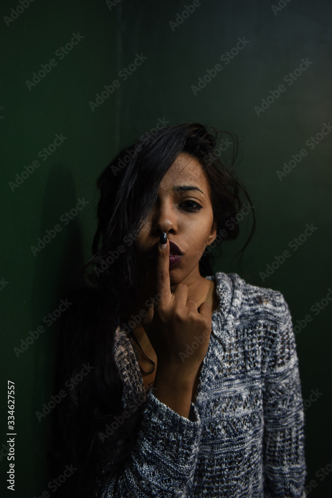 young African woman posing at studio, face with hand portrait over dark background	