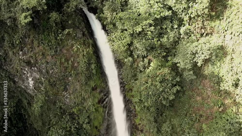 Beautiful aerial top shot of La Fortuna waterfall in Costa Rica, with nature all around it and popping colors everywhere. The waterfall is enormous and end in a beautiful swimming spot at the bottom. photo