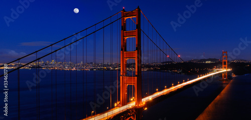 Panorama of Golden Gate Bridge and San Francisco skyline at night with rising moon
