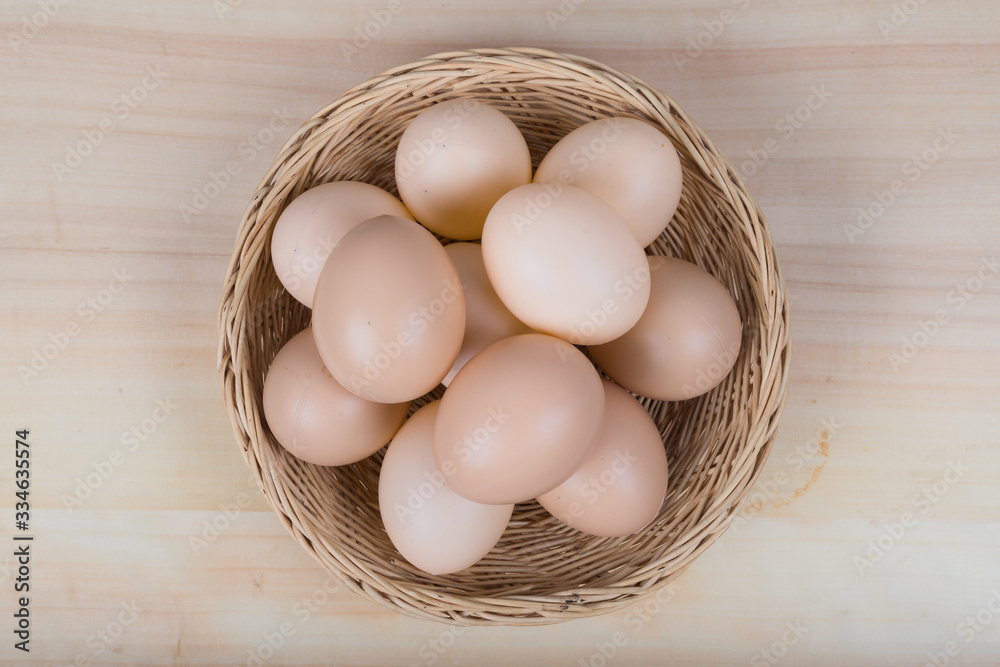 Several eggs were placed in a wooden basket on a wooden table. Several eggs were placed in a wooden basket on a wooden table.
