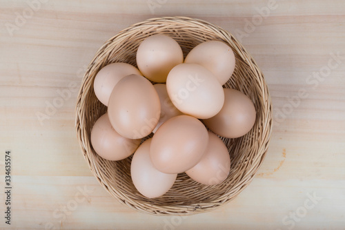 Several eggs were placed in a wooden basket on a wooden table.