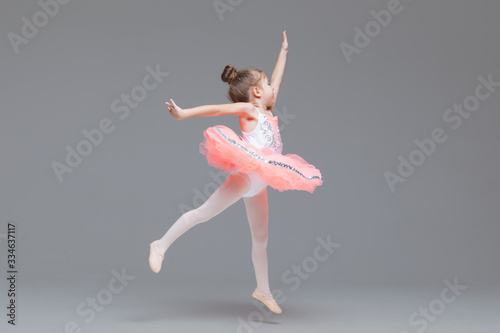 Cute adorable ballerina little girl in pink tutu dance practices ballet dancing