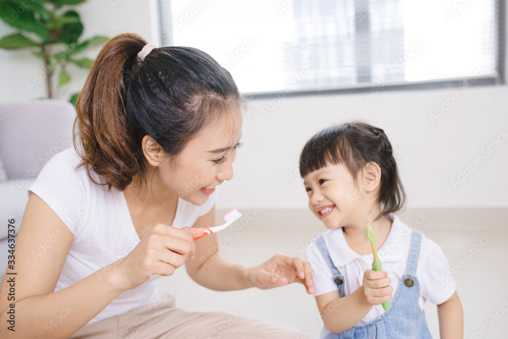 Mother teaching kid daughter teeth brushing at home Mother teaching kid daughter teeth brushing at home
