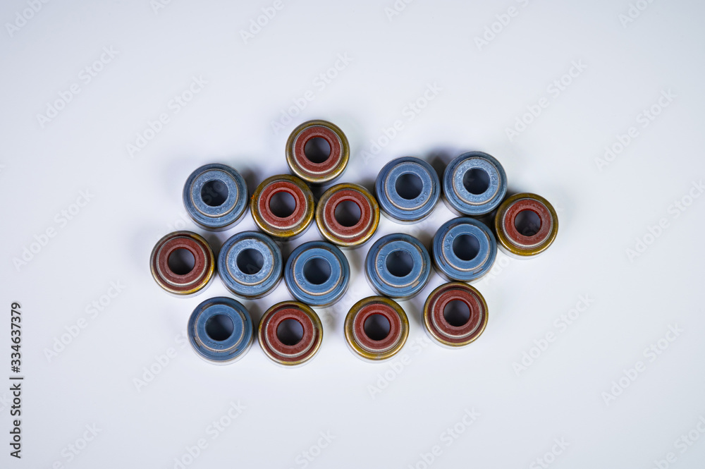 New spare parts for an internal combustion engine. Oil seals of exhaust and solenoid valves. A lot of oil seals on a gray background