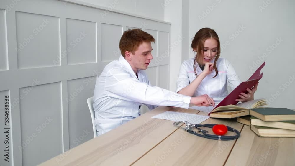 The doctor showing a colleague the story of the illness of his patient The doctor showing a colleague the story of the illness of his patient