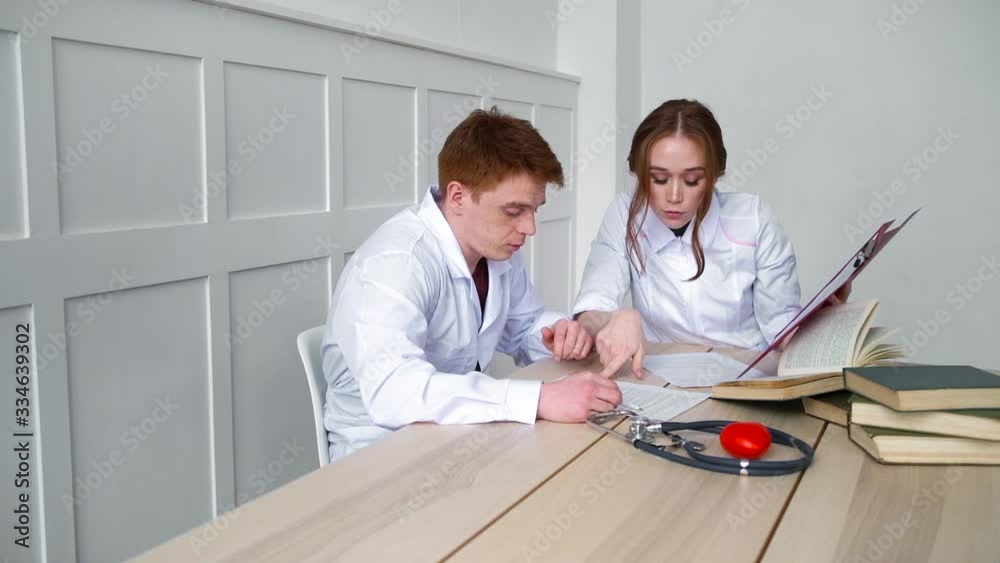 Doctor explains to student- resident how to treat patients sick with new virus Doctor explains to student- resident how to treat patients sick with new virus
