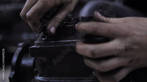 Man hands wring bolts into the gearbox cover. Hands in oil and dirty