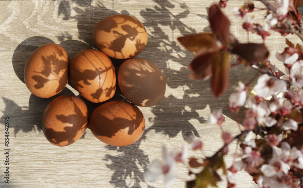 Easter concept. Many eggs lie on a table under a branch of blooming cherry. Easter concept. Many eggs lie on a table under a branch of blooming cherry.