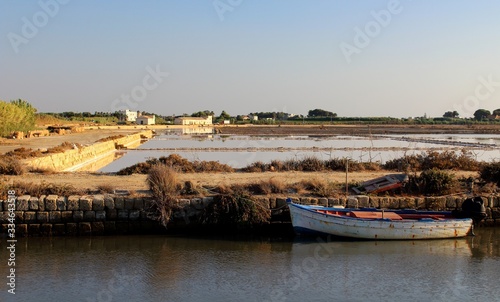 salt flats at sunset with fishing boat in the foreground and a building in the background