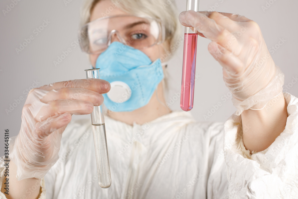 A girl in a protective suit and a respirator to protect health from viral, epidemic and infectious diseases. New Covid-19. Vaccine search concept. Stop the virus. Close-up. A girl in a protective suit and a respirator to protect health from viral, epidemic and infectious diseases. New Covid-19. Vaccine search concept. Stop the virus. Close-up.