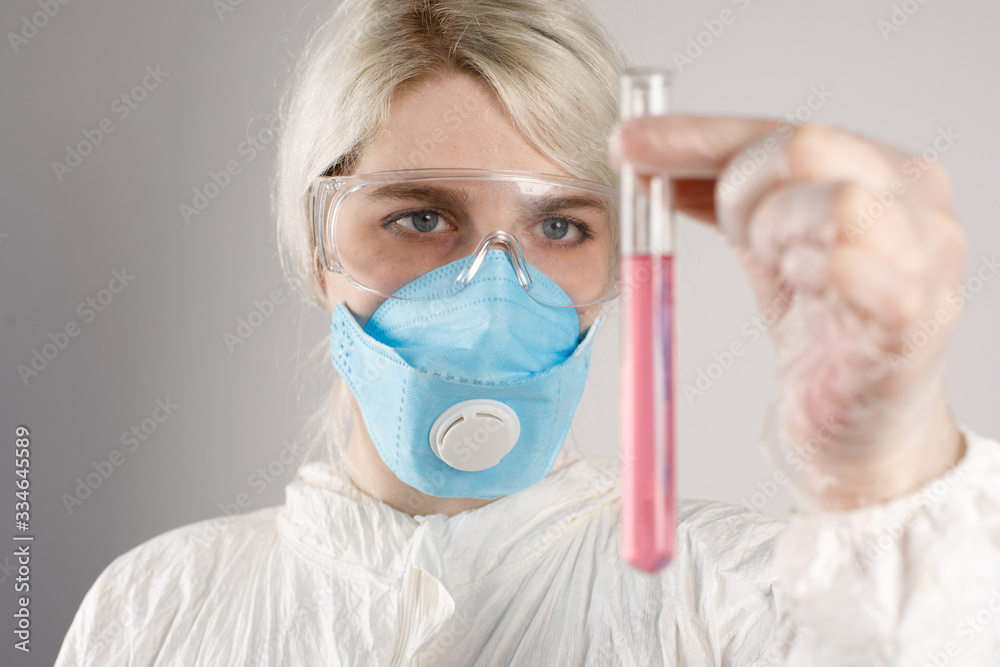 A girl in a protective suit and a respirator to protect health from viral, epidemic and infectious diseases. New Covid-19. Vaccine search concept. Stop the virus. Close-up.