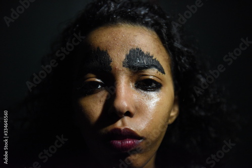 A young sensual girl with creative make-up.  black shadows painted on her face. Conceptual idea.
