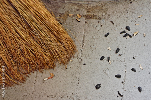 Broom close-up near the husk of seeds on the floor, sweeping garbage in publi photo