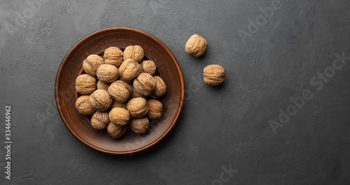 Whole walnuts on black stone background. Above view, flat lay. Copy space for text.