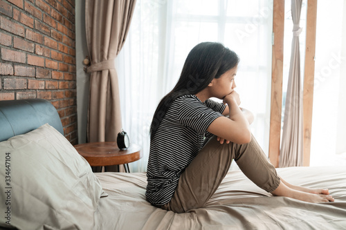 portrait of asian sad teenager sitting on the bed