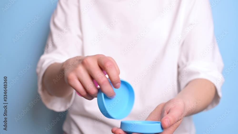 Woman hand holding menstrual cup. A woman shows a container for the menstrual cup and how to use it. Alternative feminine hygiene product during the period