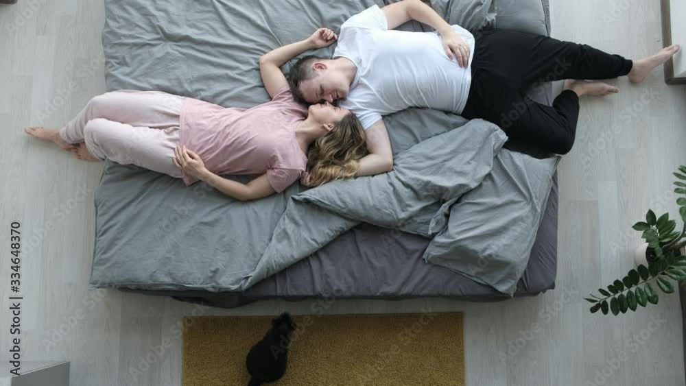 The young lovely couple and cat lying in a bed The young lovely couple and cat lying in a bed
