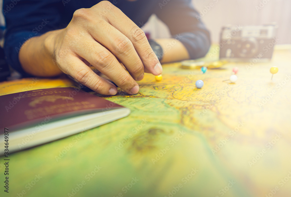 Man's hand marking area on the world map with the pin. Selective focused. Vintage tone style. Man's hand marking area on the world map with the pin. Selective focused. Vintage tone style.