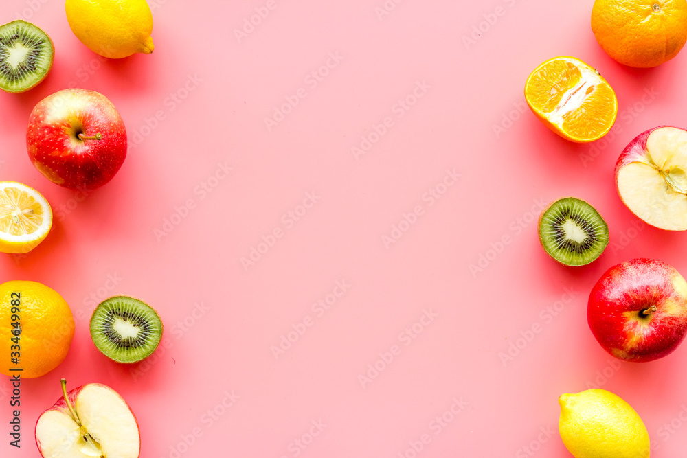 Oranges, lemon, apple, kiwi and grape - healthy food concept with fruits - on pink background top-down frame copy space
