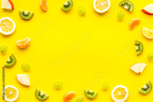 Slices fruites frame. Fruit salad concept with citruses, aplle and kiwi on yellow background top-down copy space