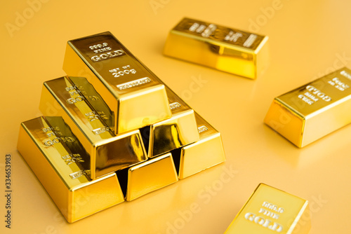 Gold bars or bullion stack on yellow background. Financial, global world economic or gold trading in commodity market concept. It performs well during global crises.