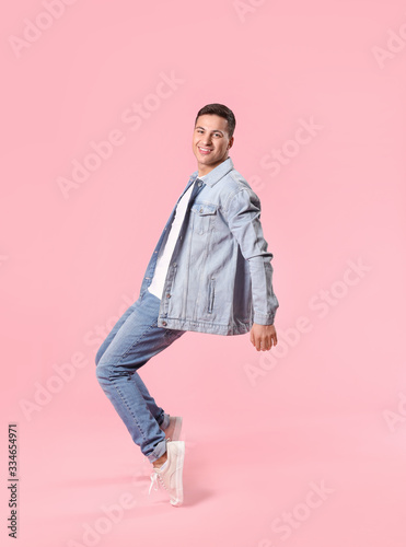 Dancing young man on color background