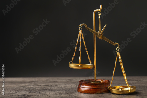 Scales of justice on table against dark background
