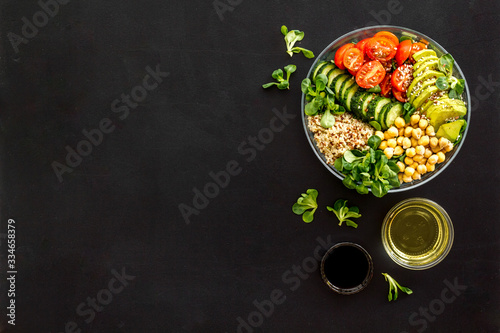 Vegan bowl. Avocado, quinoa, tomato, spinach and chickpeas vegetables salad on black table top-down copy space