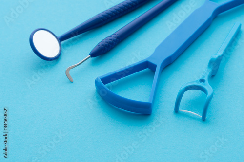 Oral care kit dental cleaning tools (tongue cleaner, mirror, dental floss) on blue background with copy space. Dental and healthcare concept.