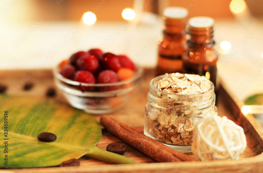 Home spa relaxing set, preparing handmade organic facial scrub with oats, cinnamon, essential oils. Calming candle lights background, beauty treatment ingredients on bath shelf. Home spa relaxing set, preparing handmade organic facial scrub with oats, cinnamon, essential oils. Calming candle lights background, beauty treatment ingredients on bath shelf.
