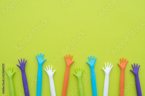 Many colorful hands up on green background with copy space. Concept of festival, party, celebration fun joy or save the earth.