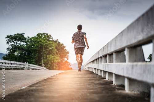Billede på lærred asian teenager running along the bridge in sprinting action, exercising or pract