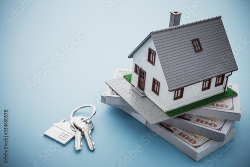 House model, bill dollar banknotes and key on blue background with copy space. Money saving for new house, home loan, reverse mortgage and real estate property business concept photo