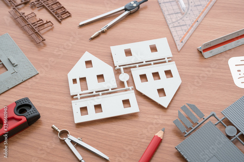 Top view of house model, pencil, ruler, dividers and other tools on wooden architects table. Creative home design and construction for remodel, real estate and property business concept.