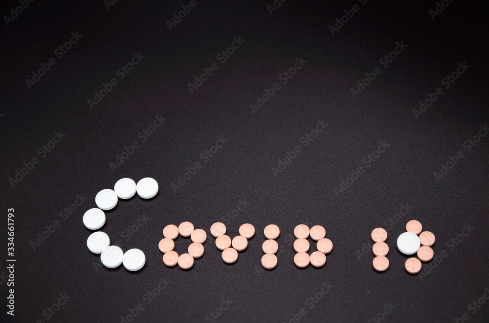 white and pink tablets and pink and yellow capsules on a black background. Coronavirus Covid-19. Copyspace. white and pink tablets and pink and yellow capsules on a black background. Coronavirus Covid-19. Copyspace.