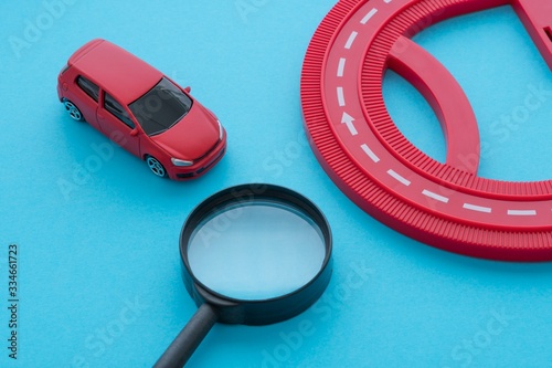 Red car, road and magnifying glass on blue background. Auto insurance business concept. Check car insurance quote for get the best deal. Cover life, property damage, injury of third party